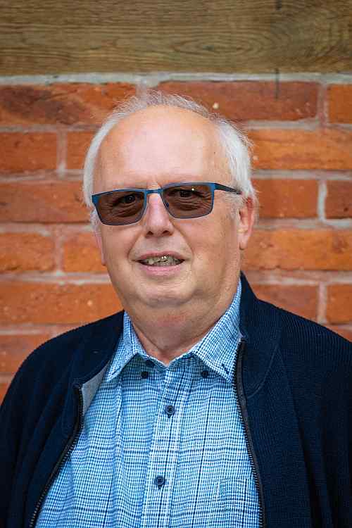 Älterer Mann mit Sonnenbrille vor Backsteinwand